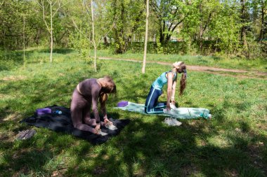 Parktaki minderlerde yoga yapan iki genç kız arkadaş.
