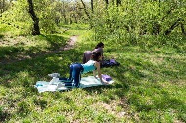 Parktaki minderlerde yoga yapan iki genç kız arkadaş.