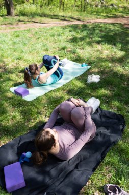 Parktaki minderlerde yoga yapan iki genç kız arkadaş.