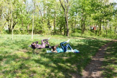 Parktaki minderlerde yoga yapan iki genç kız arkadaş.