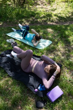 Parktaki minderlerde yoga yapan iki genç kız arkadaş.