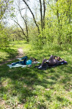 Parktaki minderlerde yoga yapan iki genç kız arkadaş.