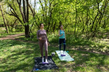 Parktaki minderlerde yoga yapan iki genç kız arkadaş.