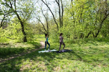 Parktaki minderlerde yoga yapan iki genç kız arkadaş.