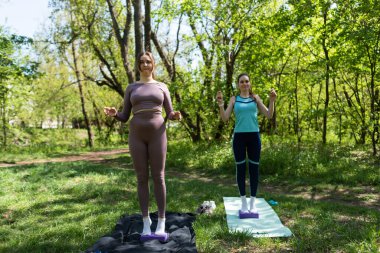 Parktaki minderlerde yoga yapan iki genç kız arkadaş.