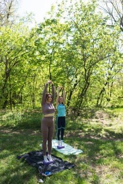 Parktaki minderlerde yoga yapan iki genç kız arkadaş.
