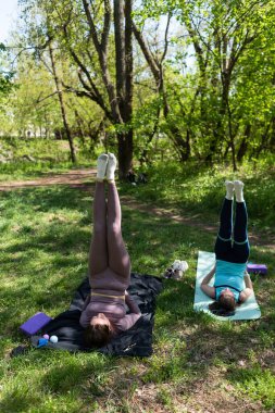 Parktaki minderlerde yoga yapan iki genç kız arkadaş.