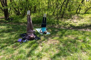 Parktaki minderlerde yoga yapan iki genç kız arkadaş.