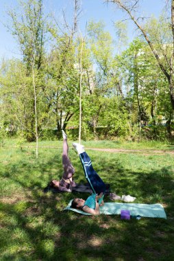 Parktaki minderlerde yoga yapan iki genç kız arkadaş.