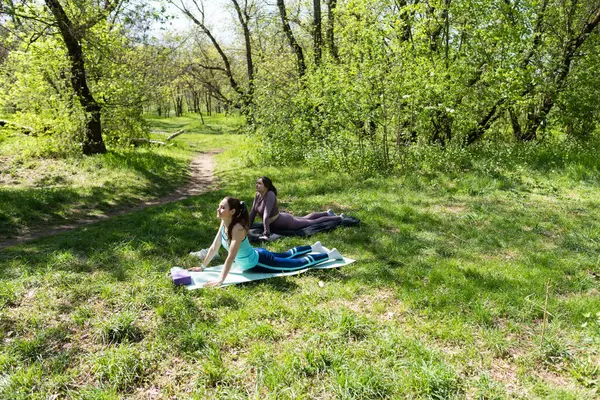 Parktaki minderlerde yoga yapan iki genç kız arkadaş.