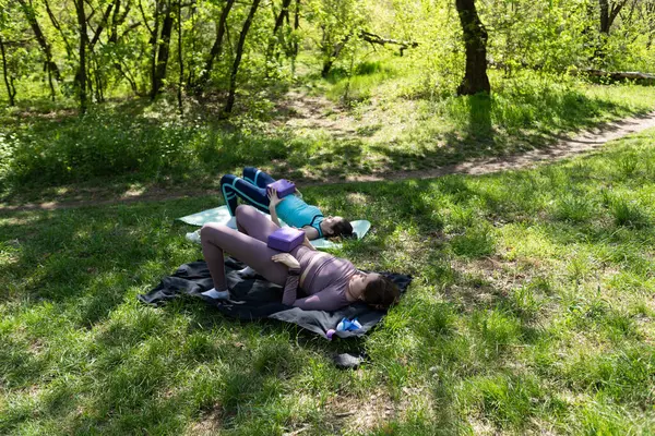 Parktaki minderlerde yoga yapan iki genç kız arkadaş.