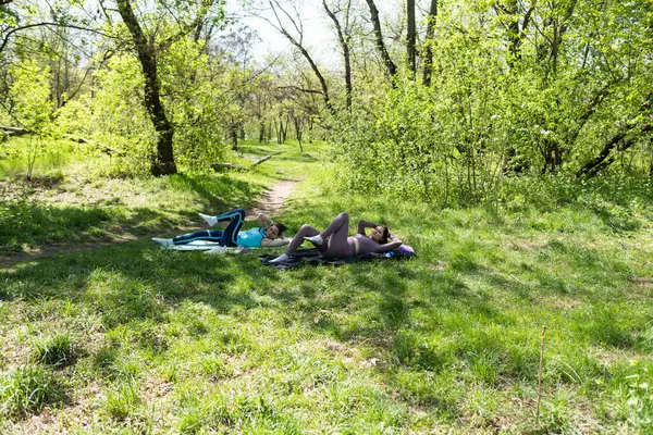 Parktaki minderlerde yoga yapan iki genç kız arkadaş.