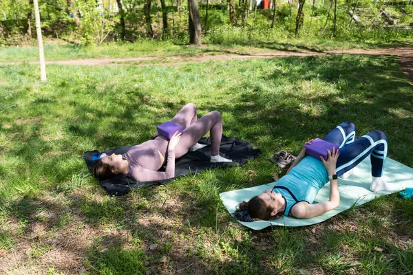 Parktaki minderlerde yoga yapan iki genç kız arkadaş.