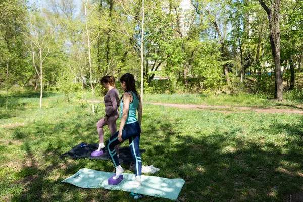 Parktaki minderlerde yoga yapan iki genç kız arkadaş.