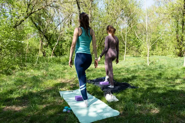 Parktaki minderlerde yoga yapan iki genç kız arkadaş.