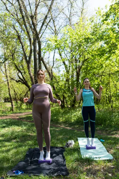 Parktaki minderlerde yoga yapan iki genç kız arkadaş.