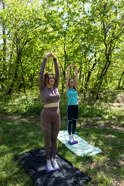 Parktaki minderlerde yoga yapan iki genç kız arkadaş.