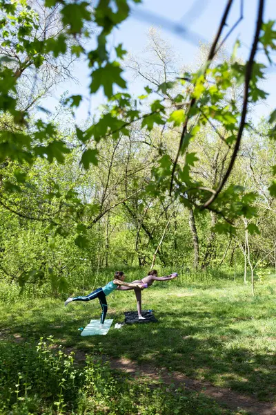 Parktaki minderlerde yoga yapan iki genç kız arkadaş.