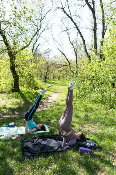 Parktaki minderlerde yoga yapan iki genç kız arkadaş.