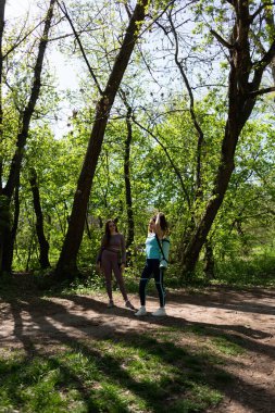 Spor takım elbiseli iki genç kız parkta fiziksel egzersizden sonra yürüyorlar. 
