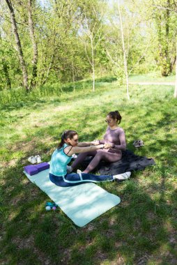 Parktaki minderlerde yoga yapan iki genç kız arkadaş.