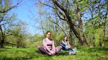 Parktaki minderlerde yoga yapan iki genç kız arkadaş.