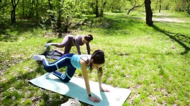 Parktaki minderlerde yoga yapan iki genç kız arkadaş.