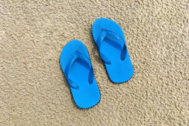 Kumsaldaki kumsalda bir çift mavi sandalet.