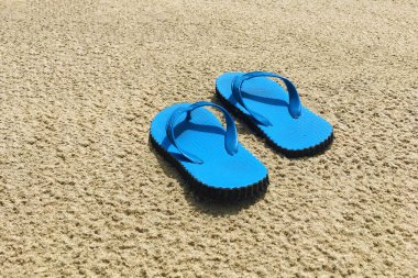 Kumsaldaki kumsalda bir çift mavi sandalet.