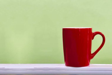 Yumuşak yeşil arkaplan ve telif alanı olan çıkıntıda kırmızı kupa