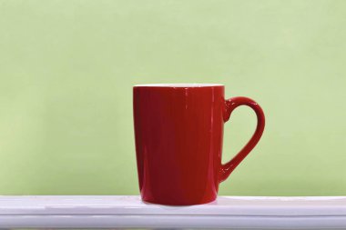 Kenarında kırmızı bardak ve hafif yeşil arka plan.