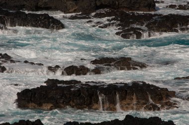 Deniz dalgaları kayalık bir sahilde kırılıyor