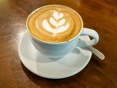 Bir fincan sıcak kahve kapuçino latte sanat seramik bir demlikte ahşap arka planda.