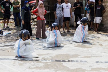 Yogyakarta, Endonezya. 14 Ağustos 2022: Çocuklar kask takıp Endonezya 'nın bağımsızlık gününü kutlamak için çuval yarışı yapıyorlar