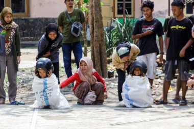 Yogyakarta, Endonezya. 14 Ağustos 2022: Çocuklar kask takıp Endonezya 'nın bağımsızlık gününü kutlamak için çuval yarışı yapıyorlar