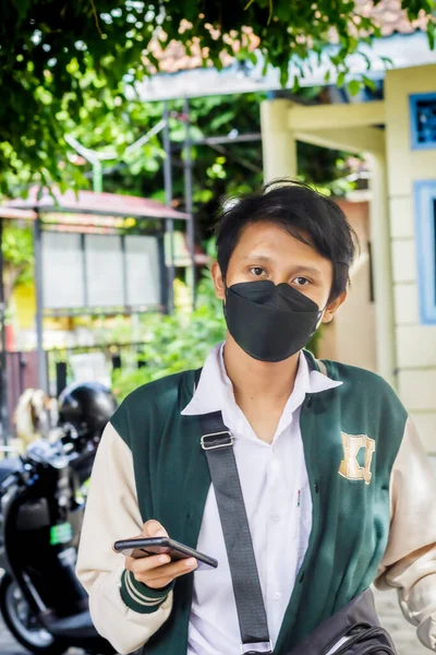 印度尼西亚日惹 2022年7月22日 一位高中时的年轻人 他的右手拿着智能手机 手里拿着相机 — 图库照片