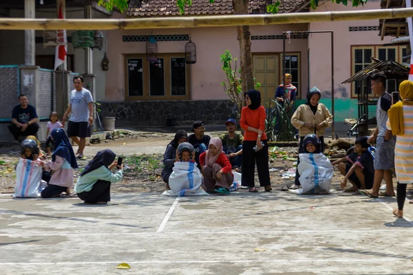 Yogyakarta, Endonezya. 14 Ağustos 2022: Çocuklar kask takıp Endonezya 'nın bağımsızlık gününü kutlamak için çuval yarışı yapıyorlar