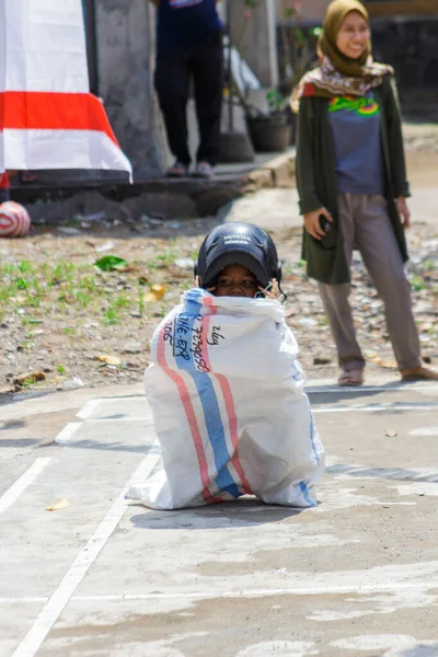 Yogyakarta, Endonezya. 14 Ağustos 2022: Çocuklar kask takıp Endonezya 'nın bağımsızlık gününü kutlamak için çuval yarışı yapıyorlar