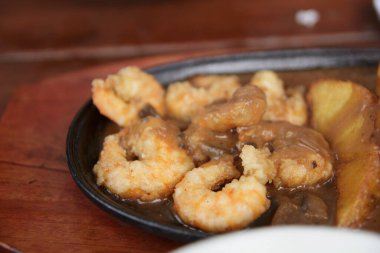 Kokteyl soslu kızarmış organik hindistan cevizi karidesi. Masadaki siyah tabakta lezzetli bir aperatif.