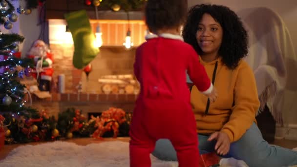 快乐的女人抱着蹒跚学步的男孩 给孩子们送圣诞礼物 充满爱心的非洲裔美国年轻母亲与儿子在舒适的客厅里共度新年的画像 — 图库视频影像