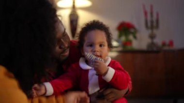 Neşeli küçük Afrikalı Amerikalı çocuğun portresi. Anne babasıyla gülüyor ve gidiyor. Mutlu kaygısız çocuk Noel arifesinde rahat bir anne ve babayla oturma odasında eğleniyor.