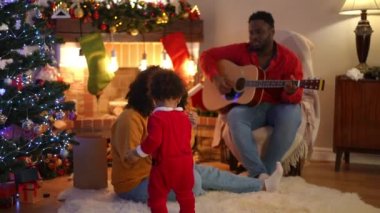 Genç Afrikalı Amerikalı anne, yeni yürümeye başlamış oğluyla şöminede gitar çalan baba kocası olarak oynuyor. Mutlu kendinden emin aile Noel 'i birlikte kutluyor.