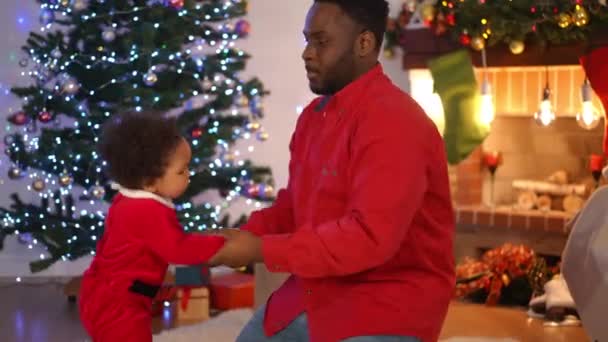 Веселий Молодий Афроамериканець Танцює Гарним Маленьким Сином Вітальні Новорічним Деревом — стокове відео