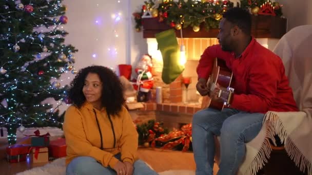 Романтичний Афроамериканець Грає Гітарі Розслабленої Дружини Яка Сидить Вітальні Різдво — стокове відео