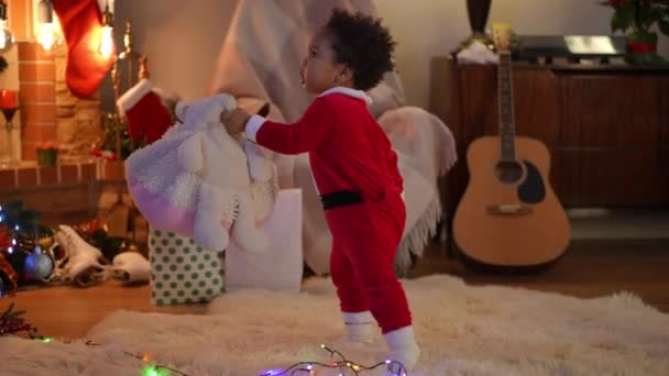 跟踪拍摄可爱的非洲裔美国小男孩带着垫子走在客厅里给一个难以辨认的白人女人的照片 快乐孩子在家中享受新年的肖像 — 图库视频影像