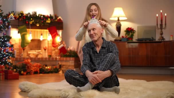 Dziadek Siedzi Dywanie Salonie Jako Wesoła Wnuczka Nastoletnia Zakładając Diadem — Wideo stockowe