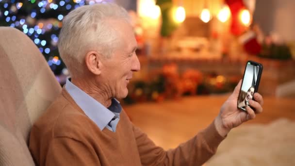 在智能手机视频聊天中 侧面视图快乐祖父在网上与孙女聊天 在圣诞前夕 笑着和白人老人和积极的少女交谈 家庭和假日 — 图库视频影像