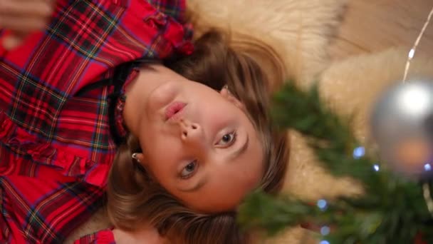 圣诞前夜 在家里 一位白种人少女躺在圣诞树下做着白日梦 她是个非常迷人的白人少女 快乐的微笑美丽的少年享受假期 生活方式和奇迹 — 图库视频影像