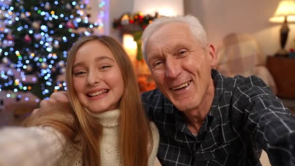 放宽心的白人祖父和孙女在家里鬼鬼祟祟地庆祝圣诞视频博客 在新年前夕的博客上 积极的年长男子和少女摆出一副积极的面孔 — 图库视频影像