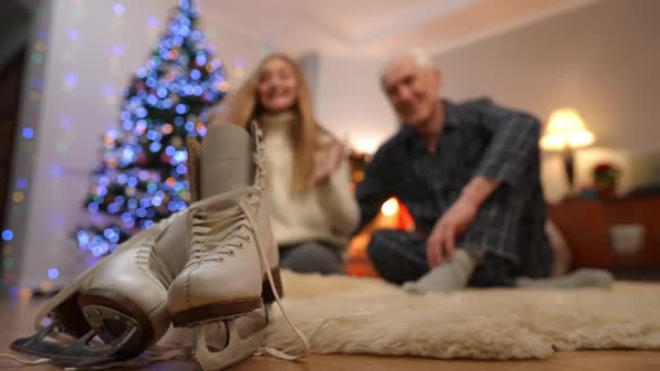 特写白色的新冰鞋在客厅里 与模糊的少女在后台欢欣鼓舞 感谢老人的圣诞礼物 无法辨认的白人孙女和祖父 — 图库视频影像